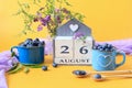 Calendar for August 26 :the name of the month of August in English, cubes with the number 26, blueberries in blue cups, bouquets Royalty Free Stock Photo