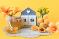 Calendar for August 18 : the name of the month of August in English, the number 18, flowers in vases, a jar of jam, apricots on a