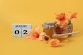 Calendar for August 2 : the name of the month of August in English, cubes with the numbers 0 and 2, honey, a jar of jam, apricots