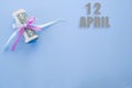 Calendar date on blue background with rolled up dollar bills pinned by blue and pink ribbon with copy space. April 12 is the