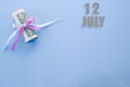 Calendar date on blue background with rolled up dollar bills pinned by blue and pink ribbon with copy space. July 12 is the