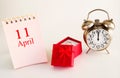 Calendar date on light background with red gift box with ring and alarm clock with copy space. Royalty Free Stock Photo