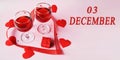 calendar date on light background with two glasses of red wine, red gift box and red hearts with copy space. December 3