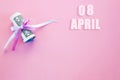 Calendar date on pink background with rolled up dollar bills pinned by pink and blue ribbon with copy space. April 8 is the eighth