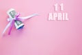 Calendar date on pink background with rolled up dollar bills pinned by pink and blue ribbon with copy space. April 11 is the