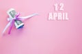 Calendar date on pink background with rolled up dollar bills pinned by pink and blue ribbon with copy space. April 12 is the