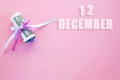 Calendar date on pink background with rolled up dollar bills pinned by pink and blue ribbon with copy space. December 12 is the