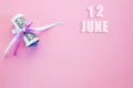 Calendar date on pink background with rolled up dollar bills pinned by pink and blue ribbon with copy space. June 12 is the