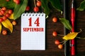 calendar date on wooden dark desktop background with autumn leaves and small apples. September 14 is the fourteenth day of the