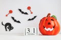 Calendar dated October 31, Jack-o-latern, black cat and bats on white table. Halloween card with selective focus