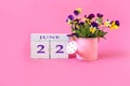 Calendar for June 22 : the name of the month of June in English, cubes with the number 22, a bouquet of violets in a pink watering