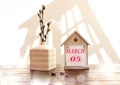 Calendar for March 5: a decorative house with the name of the month March in English, numbers 05, a bouquet of flowering willow in