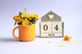 Calendar for May 4: cubes with the numbers 0 and 4, the name of the month of May in English, a bouquet of dandelions in a yellow