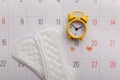 Calendar, menstrual pads and yellow alarm clock