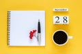 Calendar November 28 cup of coffee, notepad with pen and yellow leaf on yellow background Royalty Free Stock Photo