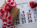 Calendar page with highlighted heart written in red on February 14 of Valentine`s Day with red heart combination, gift box. Top vi Royalty Free Stock Photo