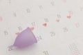 Calendar and purple menstrual cup. Women's hygiene, menstruation, critical days concept