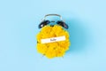 Calendar summer month July and alarm clock with yellow dandelions flowers on face, blue background. Top view Flat lay Royalty Free Stock Photo