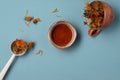 Calendula dried herbs in orange craft cup with honey on blue background. Royalty Free Stock Photo