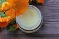 Calendula flowers and diy face cream in glass jar on wooden table background with copy space. Homemade natural organic cosmetics Royalty Free Stock Photo