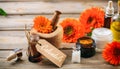 Calendula products. Essential oil, globules and cosmetics, tag with text calendula. Wooden table background Royalty Free Stock Photo