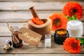 Pot marigold products. Essential oil, globules and cosmetics, tag with text marigold. Wooden table background Royalty Free Stock Photo