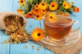 Calendula tea with fresh and dried flowers on blue wooden background Royalty Free Stock Photo
