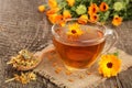 Calendula tea with fresh and dried flowers on old wooden background