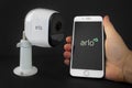 An Arlo security camera with an iPhone Plus hold by a person using the Arlo aplication