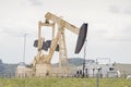 A crude oil production well, a site with a pump jack in a rural area during summer in