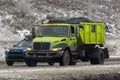 A Green Diesel Garbage Truck on the road during the winter