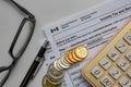 Canadian Tax Forms with coins, calculator, a pen and glasses on a white table. Tax time