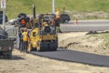 A construction worker using a Cat Tandem Vibratory Roller to compact paving asphalt for a