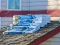 Multiple bundles of Tone Black Fiberglass Roofing Shingles positioned atop a house