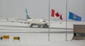 A Westjet plane with a Canadian and Albertan flag half-masting during winter