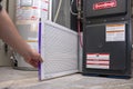 Calgary, Alberta, Canada. March 23, 2021. A person changing an clean air Filtrete 3M filter on a Goodman high efficiency furnace