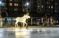 Ice skater skating in front of a moose Christmas decoration on a frozen outdoor rink