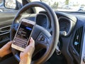 A person texting using an iPhone and driving a chevrolet car. Concept Text and drive