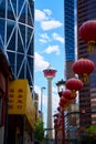 The Calgary Tower in the center of a modern city against the background of glass skyscrapers. Red Chinese lanterns in Chinatown in