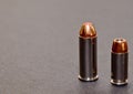 A 40 caliber hollow point bullet and a 44spl red tipped bullet together on a gray background Royalty Free Stock Photo