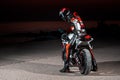 15.10.20, California, USA. The driver in a motorcycle jacket and helmet is sitting on a sportbike, looking back. Rear view. Night