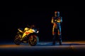 15.10.20, California, USA. A driver in a motorcycle outfit poses with his arms crossed near a sportbike. Neon light. Night