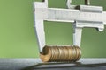 Calipers and stack of coins close-up against a green wall Royalty Free Stock Photo
