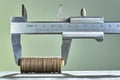 Calipers and stack of coins close-up against green wall. Royalty Free Stock Photo