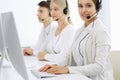 Call center. Group of operators at work. Focus on beautiful woman receptionist in headset at customer service white