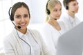 Call center. Group of operators at work. Focus on beautiful woman receptionist in headset at customer service white