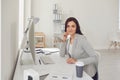 Call center operator woman in head headphones sitting at a computer in the workplace. Concept help desk on-line help