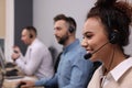 Call center operators working in modern office, focus on African American woman with headset Royalty Free Stock Photo
