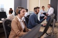 Call center operators working in modern office, focus on young woman with headset Royalty Free Stock Photo