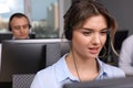 Call center operators working in modern office, focus on young woman with headset Royalty Free Stock Photo